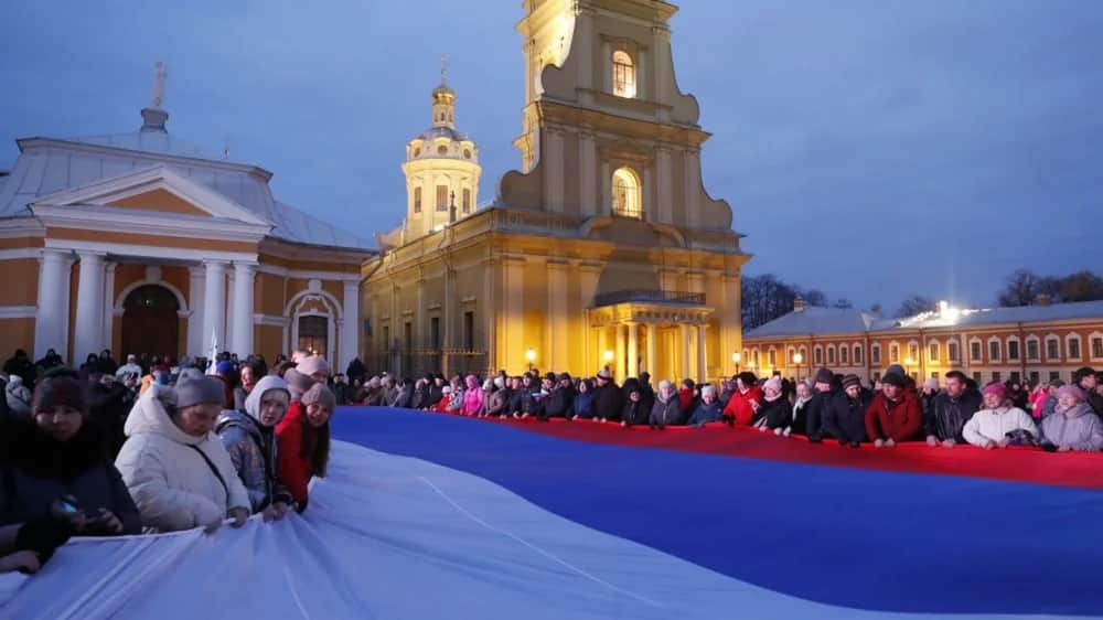 People hold a large Russian National flag during the celebration of the tenth anniversary of Russia's annexation of Crimea, in St. Petersburg, Russia, 18 March 2024. Photo: EPA-EFE/ANATOLY MALTSEV