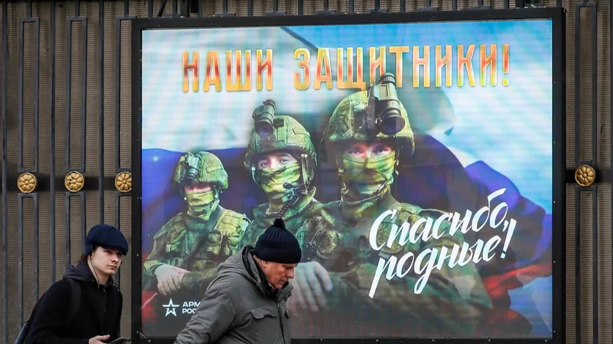 Мужчины проходят мимо экрана с изображением российских солдат и надписью «Наши защитники! Спасибо, родные» в Москве, 24 января 2024 года. Фото: Юрий Кочетков / EPA-EFE