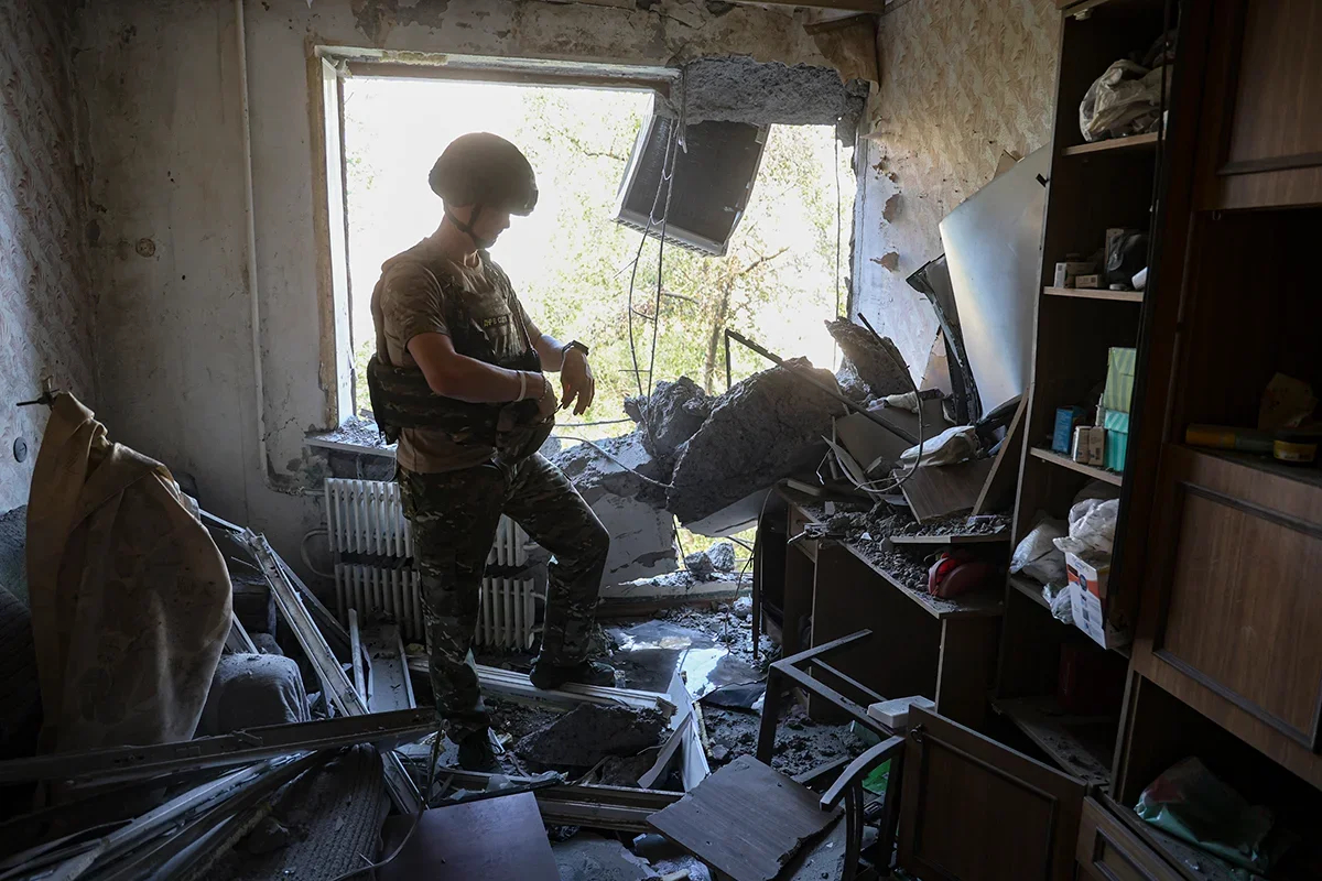 A Russian soldier examines damage caused by shelling in a residential building in the centre of Donetsk, Ukraine, 16 August 2024. Photo: Alessandro / Guerra / EPA 