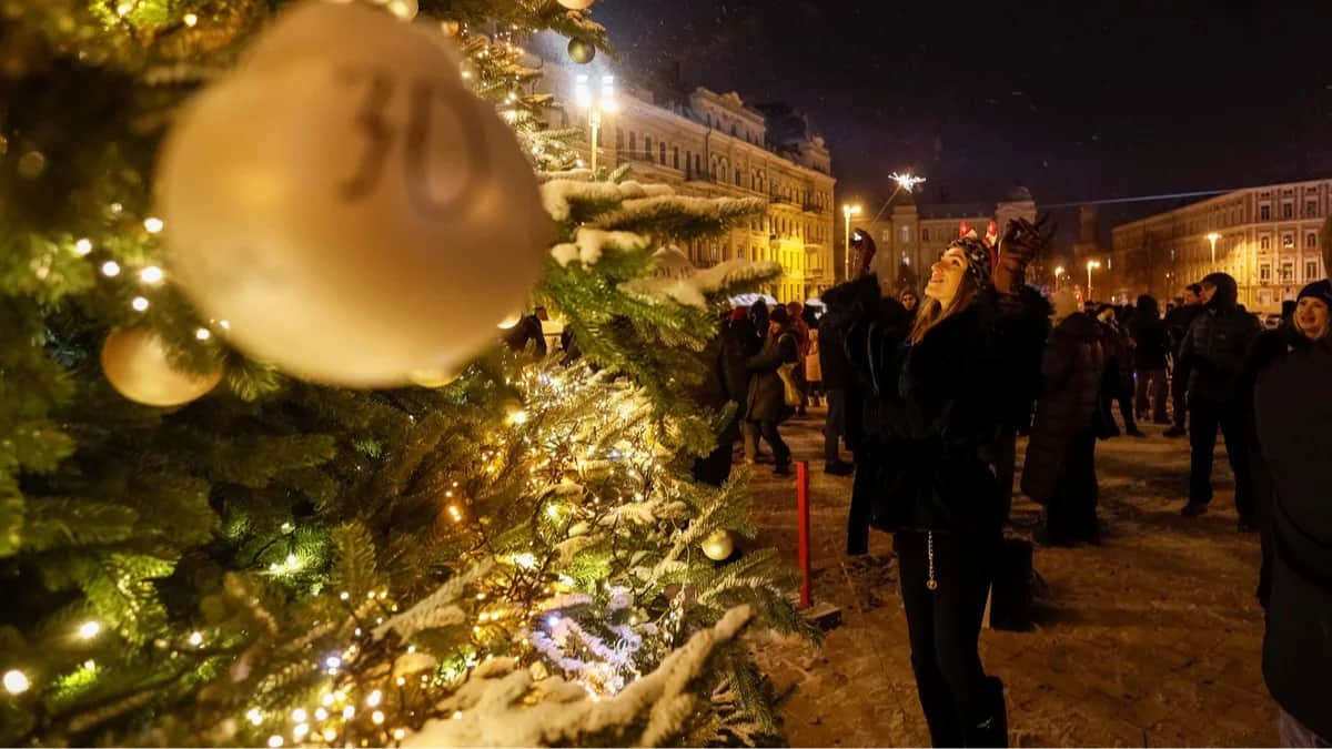 Люди собираются у новогодней ёлки, чтобы отпраздновать наступление Нового года перед введением комендантского часа на Софийской площади в Киеве, Украина, 31 декабря 2025 года. Фото: Gleb Garanich / Reuters / Scanpix / LETA