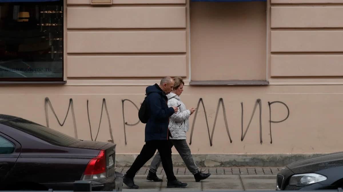 Прохожие на фоне граффити «Миру — мир» в Санкт-Петербурге, 25 марта 2022 года. Фото: Анатолий Мальцев / EPA