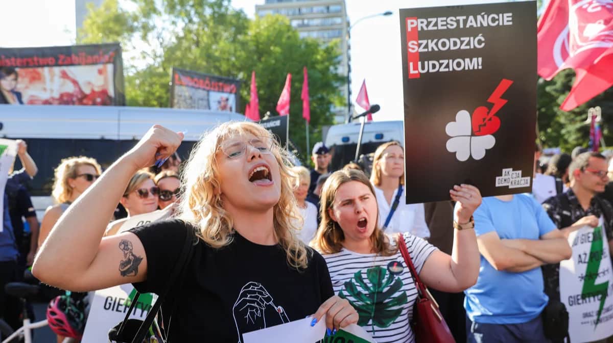 Люди с плакатом «Хватит вредить людям» на митинге «Аборт! Да!» перед зданием польского парламента в Варшаве, Польша, 23 июля 2024 года. Фото: Rafal Guz / EPA-EFE