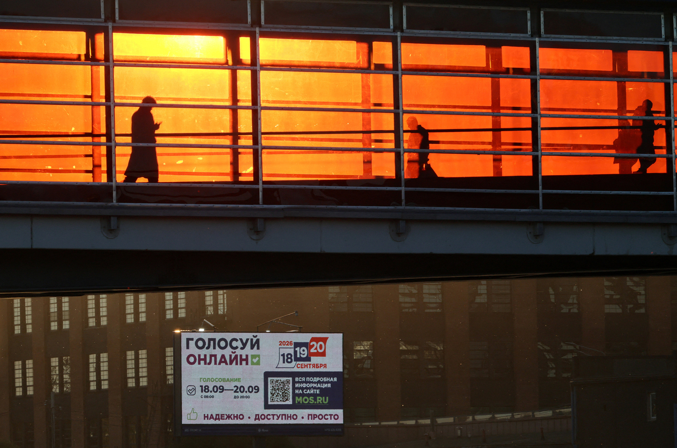 Люди идут по пешеходному мосту мимо билборда, информирующего о выборах в Госдуму. Москва. 8 сентября 2026 года. Фото: Анастасия Барашкова / Reuters / Scanpix / LETA