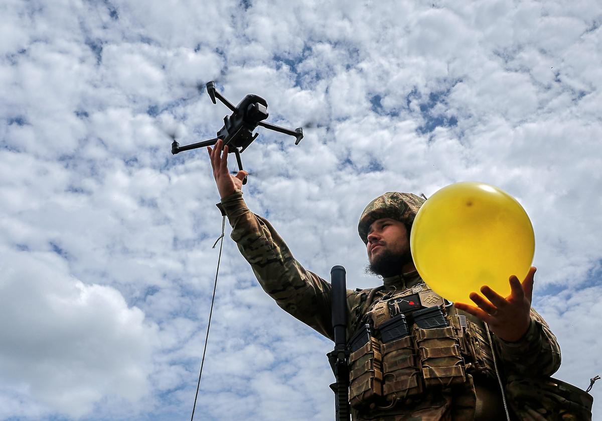 A Ukrainian serviceman lifts a drone attached to a balloon for target practice during training in the Kharkiv region, northeastern Ukraine, 30 May 2025. Photo: EPA-EFE/SERGEY KOZLOV