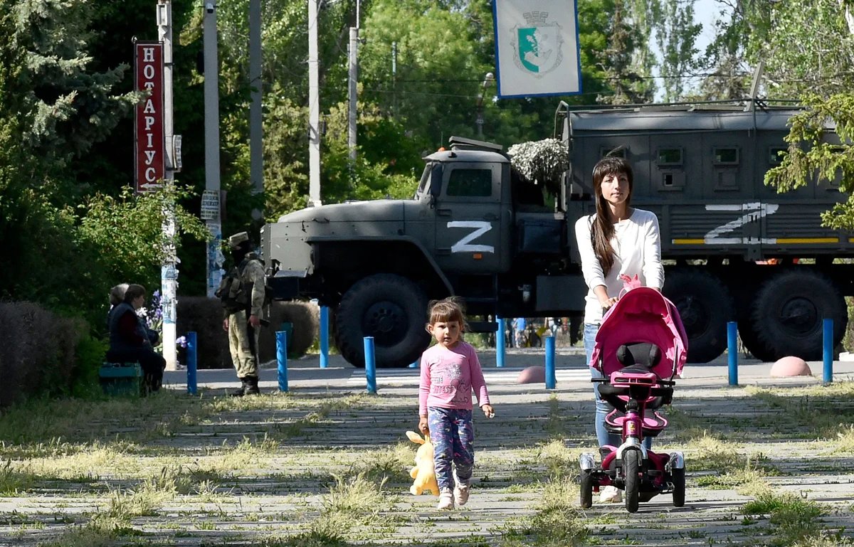 A woman and child pass Russian soldiers in Skadovsk, Zaporizhzhia region, Ukraine, 20 May 2022. Photo: Olga Maltseva / AFP / Scanpix / LETA