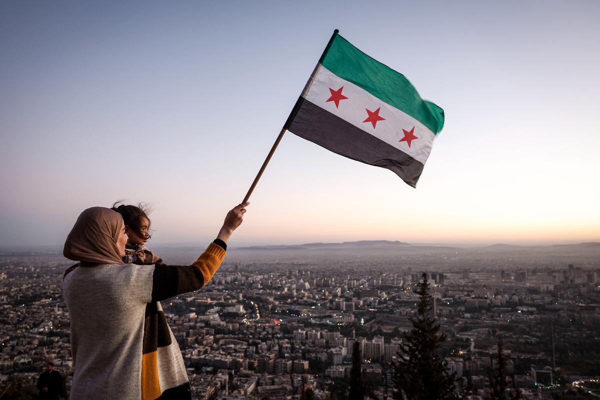 A mother and daughter wave the new Syrian flag over Damascus following the overthrow of Bashar al-Assad, 19 December 2024. Photo: EPA-EFE / ANTONIO PEDRO SANTOS