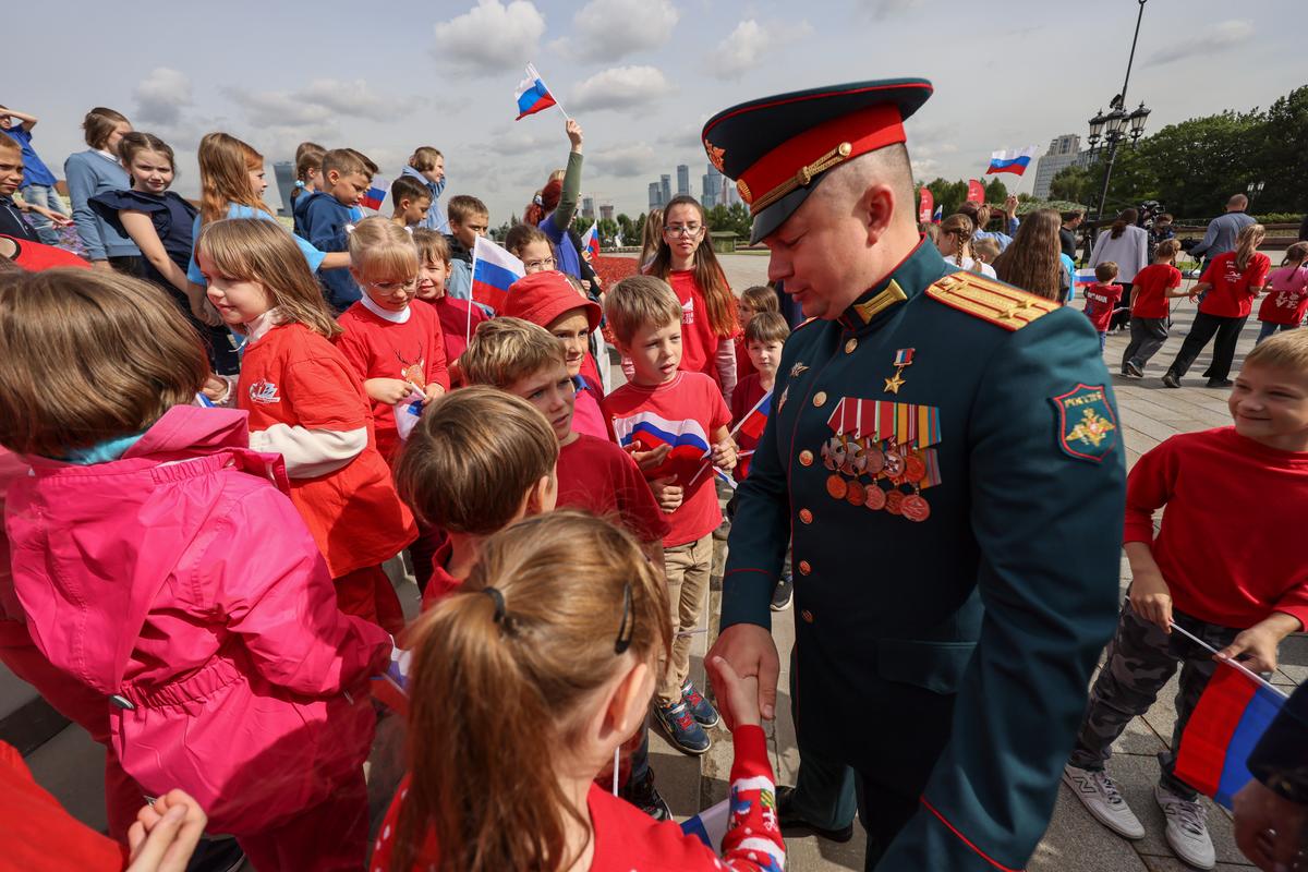 Chairman of the Movement of the First, Artur Orlov, meets children during Russian National Flag Day celebrations in Moscow, 22 August 2025. Photo: EPA/SERGEI ILNITSKY